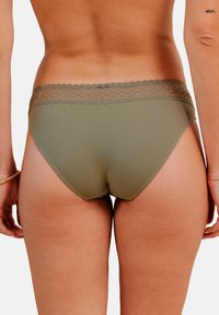 Sous-vêtements pour femmes en vert olive avec une délicate finition en dentelle à la taille, dotés d'un tissu lisse et extensible et d'une coupe mi-haute.