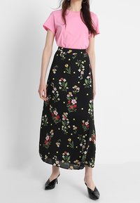 Květinová maxi sukně s černým podkladem, zdobená vícolorými květinami a žlutými tečkami; doplněná růžovým tričkem a černými balerínami.