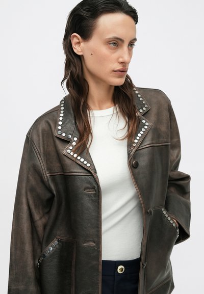 Braune Lederjacke mit einem Nietenkragen, ausgestattet mit zwei Vorderteilen und einem Knopfverschluss. Die Textur wirkt glatt mit einem leicht abgenutzten Erscheinungsbild.