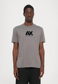 Pilkos spalvos medvilninė marškinė su apvaliu kaklu ir trumpomis rankovėmis, su juodu "AX" logotipu ir "ARMANI EXCHANGE" tekstu, centruotu priekyje.