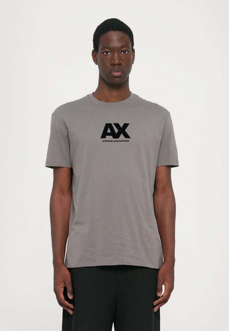 Pilkos spalvos medvilninė marškinė su apvaliu kaklu ir trumpomis rankovėmis, su juodu "AX" logotipu ir "ARMANI EXCHANGE" tekstu, centruotu priekyje.