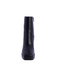 Botín negro de tobillo hecho de cuero suave, con puntera redondeada, un diseño de costura diagonal y una cremallera lateral para facilitar su uso.