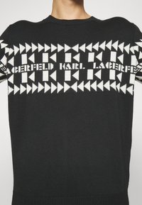 Czarny dziergany sweter z geometrycznym białym wzorem i napisem "Karl Lagerfeld" wplecionym w design. Klasyczny fason z okrągłym dekoltem.