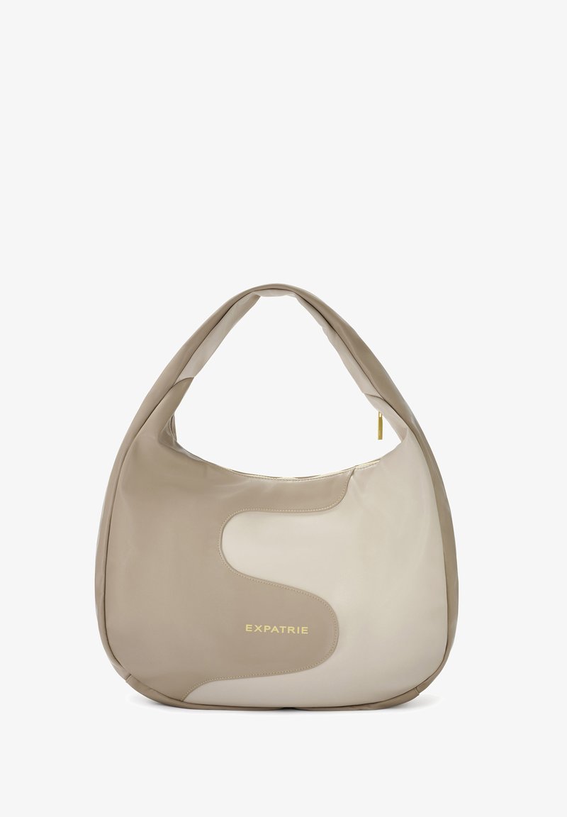 Béžová kožená hobo taška s hladkou textúrou, zakriveným tvarom a zlatým nápisom. Dvoubarevný dizajn s kontrastným panelovým detailom.