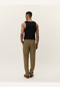 Black sleeveless tank top paired with khaki trousers, featuring a relaxed fit and classic design. Notable for its smooth texture and neutral colors.
