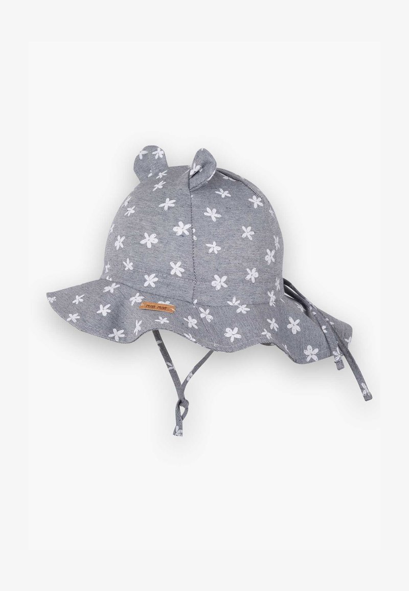 Pelēks saulessiegs ar baltu ziedu rakstu, auduma ausīm augšpusē, plata mala, regulējamas siksnas un neliela koka birka priekšā.