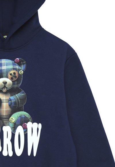 Felpa navy con un grafico di un orsetto di peluche in plaid con bottoni, accompagnato dalla parola "GROW" in grassetto bianco. Tessuto morbido.