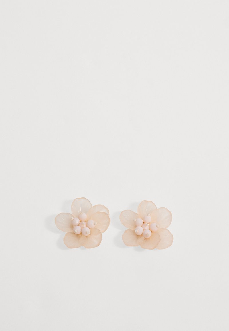 Paire de boucles d'oreilles clous beige en forme de fleur avec des pétales translucides et de petites perles rondes regroupées au centre sur un fond blanc.