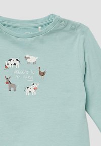 Lichtblauw hemd met lange mouwen met een boerderijthema-graphic met cartoonachtige dieren: koe, schaap, ezel, eend, en de tekst "WELKOM OP MIJN BOERDERIJ."