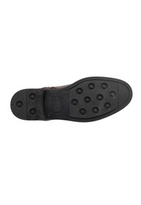Soletta di scarpa in gomma nera con un grip a trama, caratterizzata da numerosi perni arrotondati per la trazione e una sezione a tacco piatta.