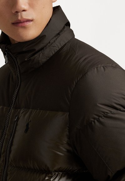 Black puffer jacket featuring a high collar, zip closure, and prominent synthetic material, with a small logo on the chest and quilted texture.