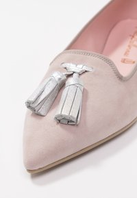 Lichtroze suède platte schoen met een puntige neus, voorzien van zilveren metallic franjes en een gladde zool. Het interieur is lichtroze.