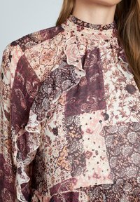 Bluse mit Floralprint, die einen hohen Rüschkragen aufweist, mit aufwendigen Mustern in Burgunderrot, Creme und Braun, aus einem weichen, leichten Stoff.