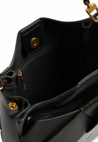 Interieur van een zwarte lederen handtas met een ritsvak voorzien van een rits met gouden kleurige trekker en een magneetsluiting.