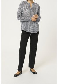 Blå och vit mönstrad långärmad blus med spetsad krage, som matchas med svarta raka byxor och svarta lägenheter.