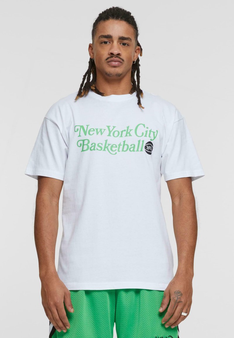 Hvid bomulds t-shirt med grøn "New York City Basketball" tekst og et sort rundt logo. Korte ærmer og afslappet pasform.