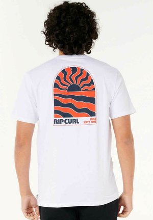 Camiseta de algodón blanca con un diseño gráfico en rojo y negro de rayos de sol y olas, con el texto "RIP CURL" y "DESDE NOVENTA" abajo.