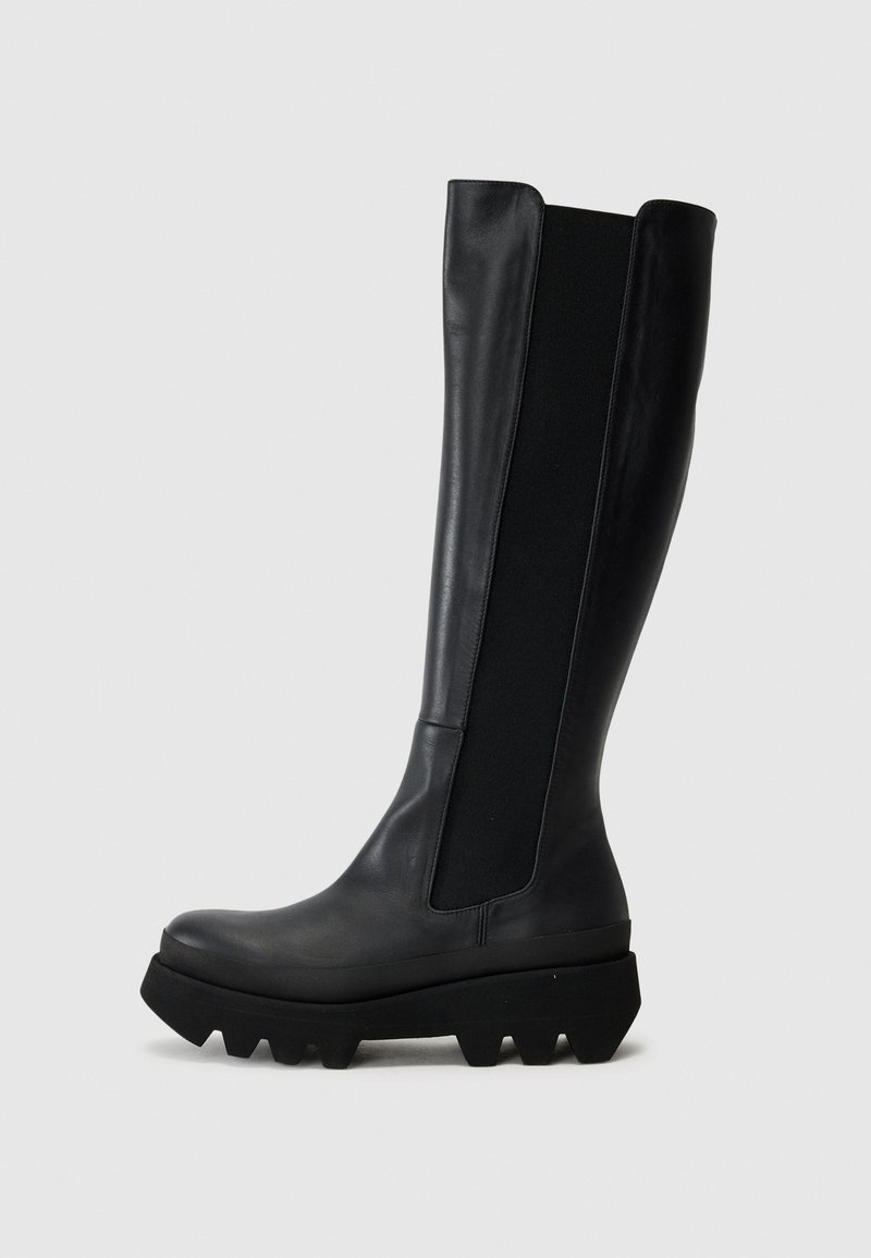 Botas de cuero negras hasta la rodilla con un acabado mate, que cuentan con paneles laterales elásticos, suela de goma gruesa y plataforma texturizada con clavos.