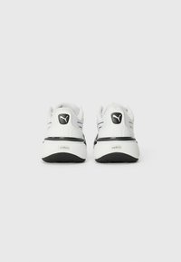 White sneakers with black accents, featuring a textured finish, padded collar, and "SOFTRIDE" branding on the heel. Standard athletic design.