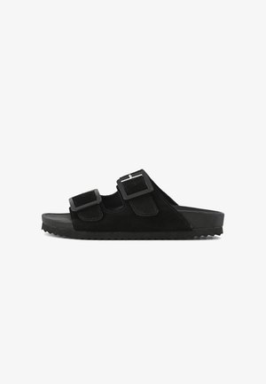 Zwarte suede instapsandalen met twee verstelbare banden met vierkante gespen, een textuur met ribbels voor grip en een minimalistisch ontwerp.