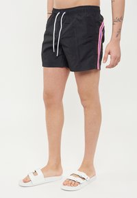 Costumi da bagno neri con vita elasticizzata, lacci bianchi e strisce laterali rosa. Realizzati in materiale leggero, lunghezza sopra il ginocchio.