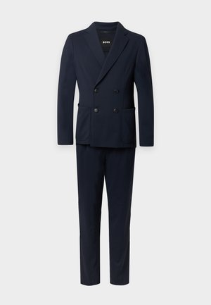 Σκούρο μπλε διπλόστροφο κοστούμι με δομημένο πέτο, δύο εμπρόσθιες τσέπες και ταιριαστό παντελόνι. Κατασκευασμένο από υφασμα με υφή.