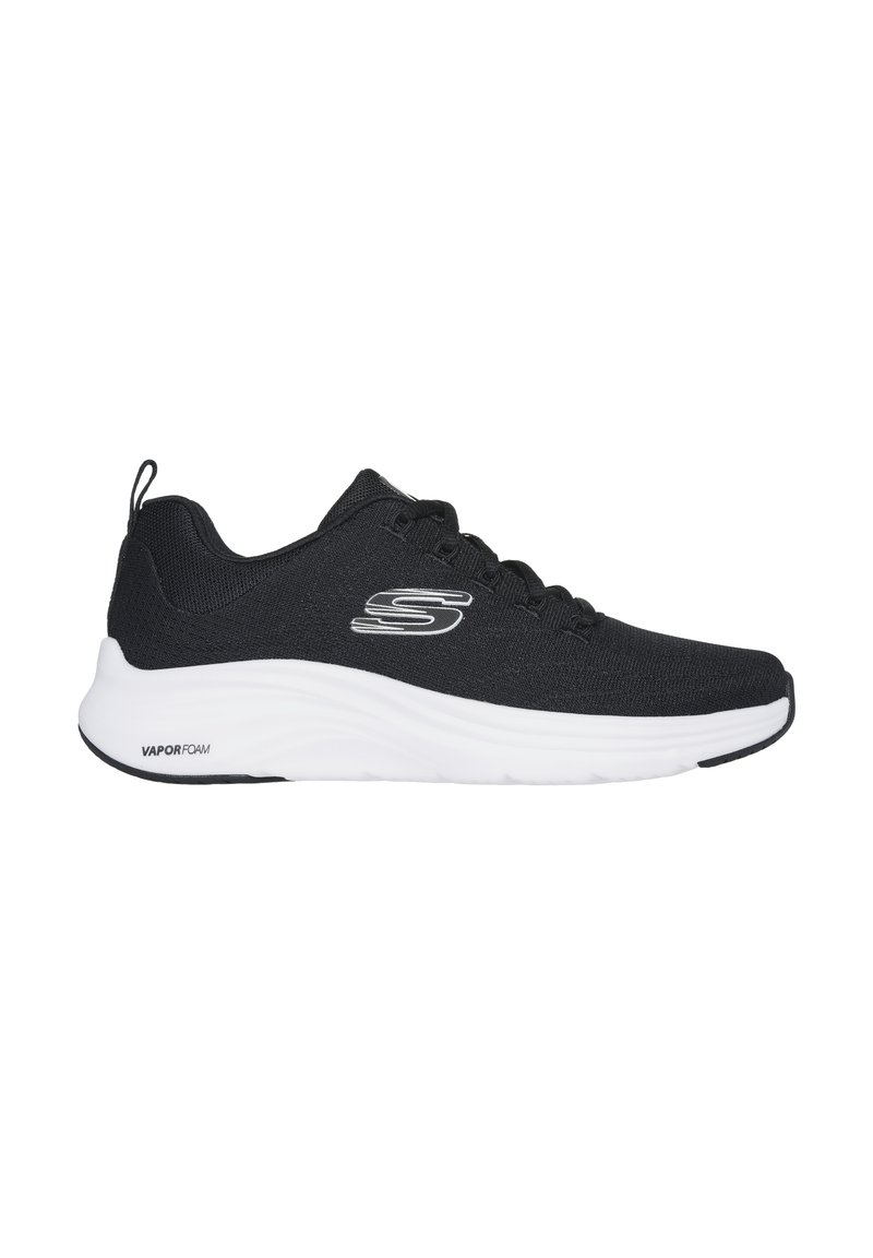 Zapatilla deportiva negra con parte superior de textil, cierre de cordones y suela de espuma blanca. Presenta un logotipo en el costado y una pestaña en el talón.