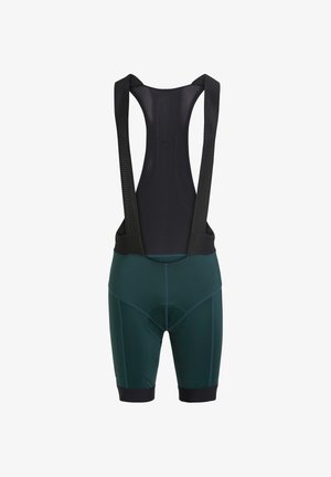 Donkergroene fietsbroek met bretels, voorzien van een zwart mesh paneel aan de achterkant en brede zwarte schouderbanden, een gevoerd zitgedeelte en aansluitende broekspijpen.