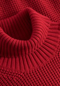 Czerwony sweter z wełny, posiadający wysoki, prążkowany kołnierz oraz teksturowany wzór ściegów. Tkanina wydaje się miękka, z widocznymi detalami ściegów.