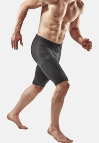 Shorts de sport noirs avec une coupe ajustée, en tissu extensible. Dotés d'une taille à cordon de serrage et de panneaux texturés sur les cuisses.