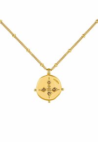 El collar de oro presenta un colgante redondo texturizado con un diseño geométrico, resaltado por pequeños acentos rojos. La cadena tiene cuentas alternadas de textura lisa y texturizada.