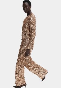 Lyserød guld to-delt sæt med pailletter, der inkluderer en løst fitting langærmet top og bredbenede bukser med en glitrende overflade.