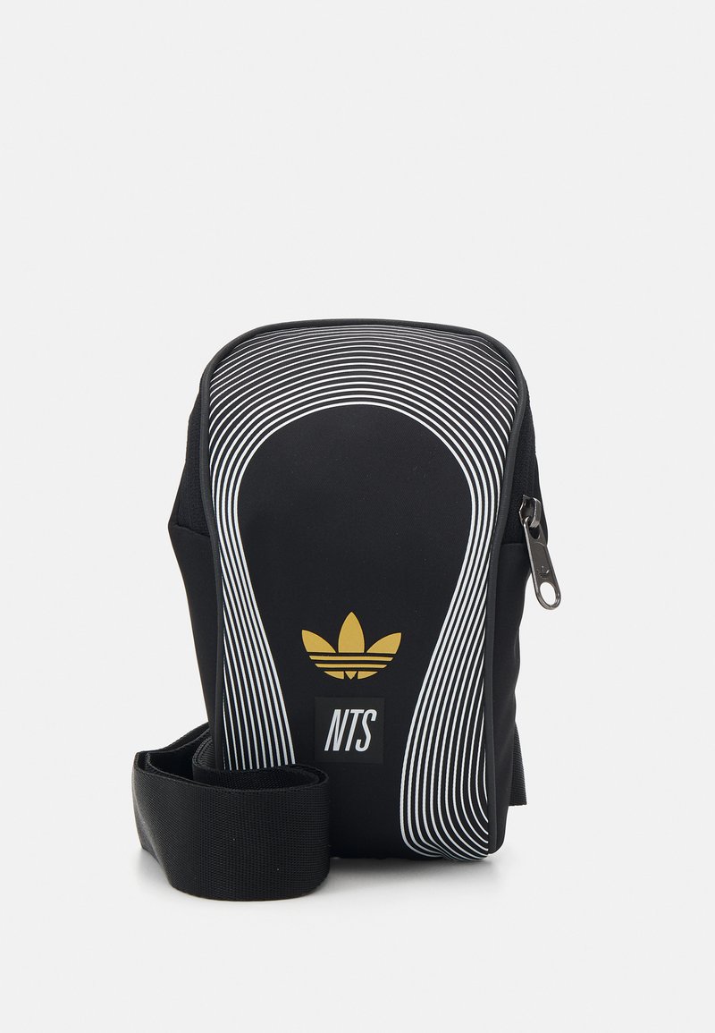 Bolso de hombro de tela negra con líneas curvas blancas, logo dorado y etiqueta "NTS". Cuenta con un cierre de cremallera y una correa ajustable.