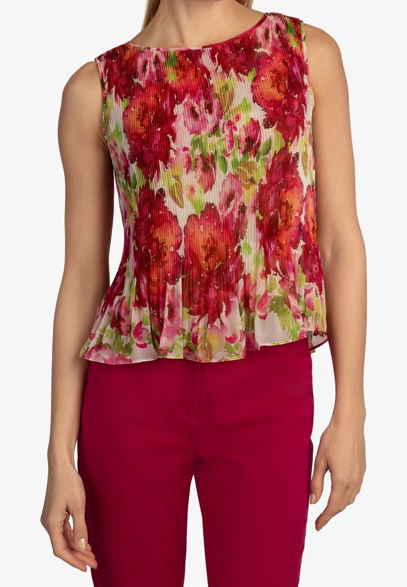 Débardeur fleuri sans manches avec texture plissée, arborant des couleurs vives rose, rouge et vert sur un fond clair. Encolure bordée.