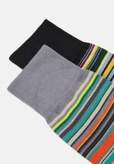 To par med sokker, en svart og en grå med fargerike striper, som har et teksturert strikket stoff og et blandet mønster.