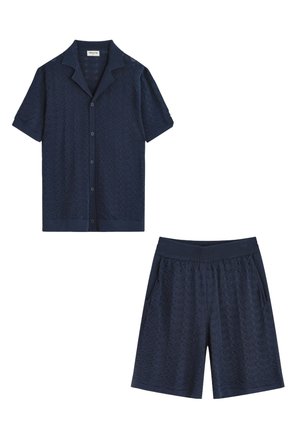 Chemise bleu marine à manches courtes avec boutons et short assorti à taille élastique avec motif chevron texturé, tous deux conçus pour une tenue décontractée.