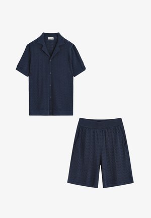 Chemise bleu marine à manches courtes avec boutons et short assorti à taille élastique avec motif chevron texturé, tous deux conçus pour une tenue décontractée.