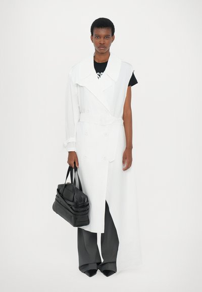 Λευκό παλτό διπλής όψης με υπερμεγέθη γιακά, συνδυασμένο με γκρίζες παντελόνες φαρδιάς γραμμής και μαύρη τσάντα. Απαλή υφή υφάσματος.