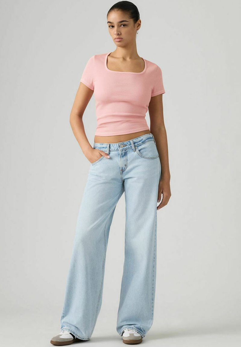 Light pink fitted ribbed top with a square neckline, paired with wide-leg light blue jeans. Sneakers complete the casual look.