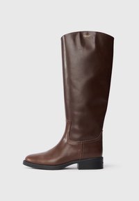 Bota de cuero marrón hasta la rodilla con un acabado suave, punta redondeada y un tacón bajo tipo bloque. Presenta un sutil detalle de costura y un logo en la parte superior.