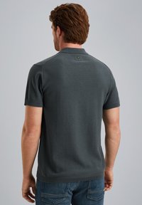 Kortærmet polo skjorte i mørkegrå strikket stof, med krave og et lille logodetail bagpå. Struktureret finish.