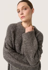 Grå tekstureret sweater med løs pasform, brede ærmer og rund halsudskæring, lavet af et blødt, fluffy materiale.