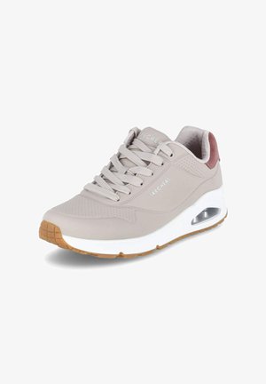Zapatilla Skechers de color gris claro con suela blanca gruesa, suela de color goma, amortiguación de aire cerca del talón y collar acolchado en tono malva, vista desde el lado frontal.