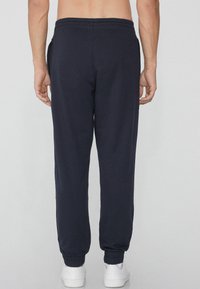 Navyblaue Jogginghosen mit elastischem Bund und Bündchen; aus weichem Material gefertigt; verfügen über seitliche Taschen; lockere Passform.