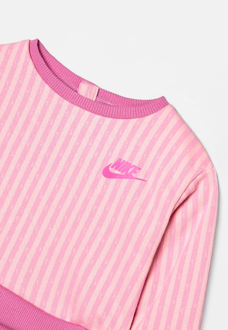 Sudadera a rayas rosas con cuello y puños acanalados. Presenta un pequeño y audaz logo de Nike en rosa en el pecho. Textura suave, diseño casual.