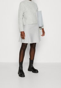 Grijze geribde trui, grijze flared rok, zwarte enkellaarsjes en een lichtgrijze handtas. Gelaagd materiaal met een casual pasvorm en minimalistisch ontwerp.