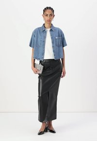 Denim jakna s kratkimi rokavi čez belo srajco, v kombinaciji z midi krilom iz črne usnja in črnimi visokimi petami. Dopolnjena s srebrno torbico.