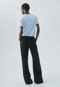 Bluet deschis, bluză cu mâneci scurte și guler rotund, asortată cu pantaloni largi negri. Textură moale, design minimalist, fără modele proeminente.