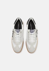 Sneaker grigie e bianche con una tomaia testurizzata, chiusura con lacci, cerniera laterale e suola in gomma. Presentano un motivo a cuore sulla linguetta.