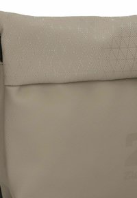 Borsa beige con texture, con un motivo a rombi trapuntato nella parte superiore e una sezione inferiore liscia, dotata di una cerniera nera.